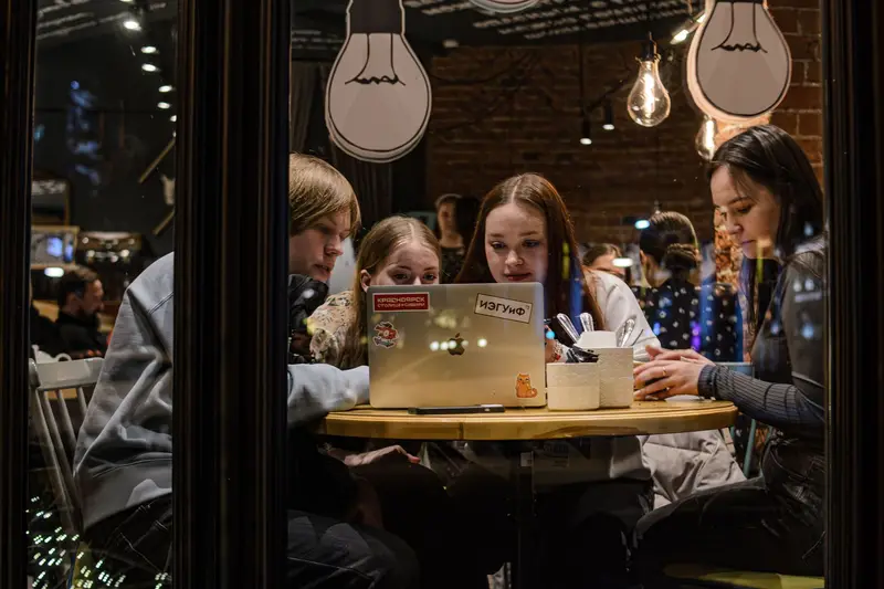 A small group gathered around a laptop in a warm café
