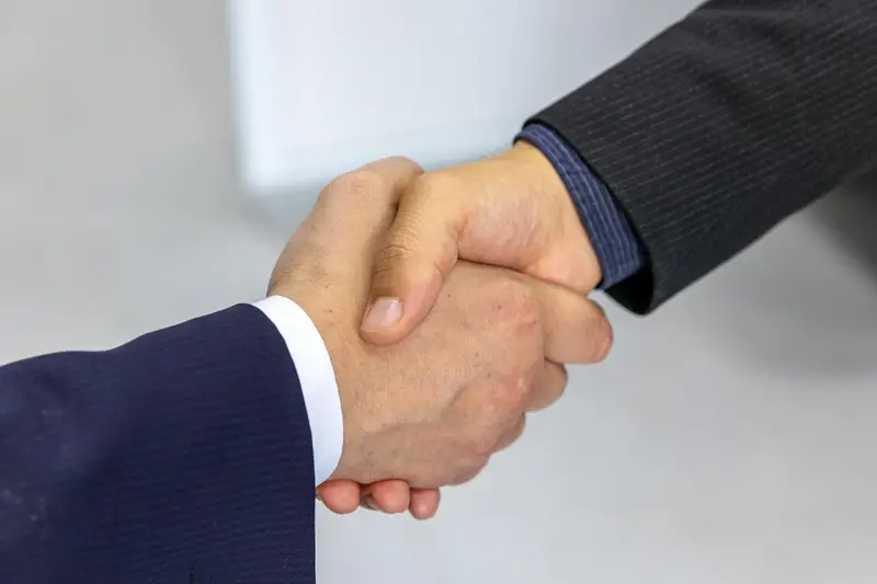 Two people shaking hands across a desk